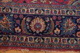 Navy blue border of vintage Meshed carpet featuring beige palmettes, cochineal red florals, and worn fringe.