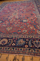 Vintage Meshed rug's ornate navy, cochineal red, and beige floral border with frayed fringe.