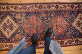 Antique Afshar runner's geometric field in brick red and indigo, with soft pile wear.