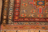 Corner of a vintage Serab runner, displaying brown field with geometric and floral motifs, and fringe.