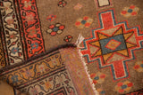 Folded corner of vintage Serab runner, revealing hand-knotted foundation, ivory fringe, and geometric starburst pile.