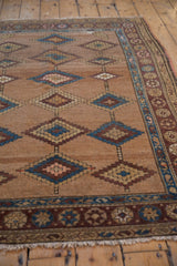 Antique Persian Hamadan rug: camel hair field with blue diamond patterns and aubergine floral border.