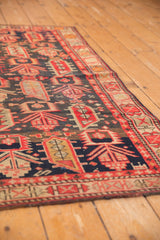 Geometric tribal patterns and border of a vintage Caucasian rug in deep indigo and red.