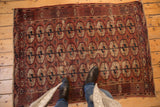 Worn antique Tekke rug's chestnut, navy, and ivory gul medallions, foundation showing.