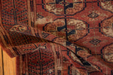 Folded antique Tekke rug, revealing germinating plant border, gul medallions, chestnut, navy, ivory.