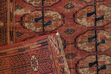 Antique Tekke rug close-up: fringed kilim end and worn chestnut, navy gul medallions.