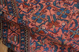Vintage Malayer rug pile showcasing raspberry red field, navy blue Herati motifs, and vine border.