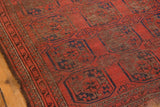 Worn madder red pile, navy gul motifs, and exposed foundation on antique Beshir rug.