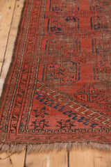 Antique Beshir rug corner: madder red guls, navy patterns, pile wear, secured fringe.