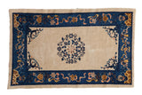 Antique Chinese Peking rug, central multi-petalled floral motif, ivory field, cobalt blue border.