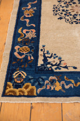 Inwardly pointing tree motif on ivory field within antique Peking rug's cobalt border.