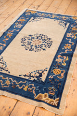 Corner of an antique Peking rug, revealing cobalt border vinery, gold motifs, and worn side.