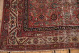 Antique Malayer rug corner, madder root red meandering vine border, worn Herati field, and fringe.