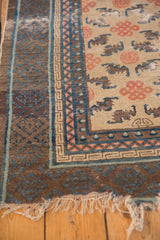 Corner detail of an Antique Ningxia rug runner, with endless knot and bat motifs, blue borders, and aged fringe.