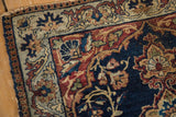 Antique Kermanshah rug corner: navy blue field with scrolling tendrils and pawn motif border.