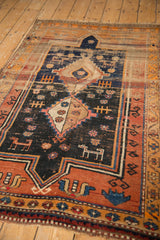 Stylized animals, terra cotta border, and visible pile wear on the vintage Caucasian rug.