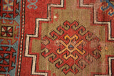 Vintage Caucasian rug detail: cherry red stepped contour, floral gul, and visible pile wear.