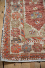 Distressed Oushak rug runner corner, textured pile, pomegranate, sand, silver tones, intact selvage.