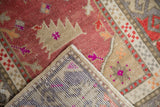 Distressed vintage Oushak rug corner revealing low raspberry red pile and hand-knotted reverse.