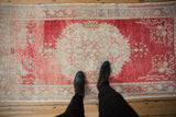Distressed vintage Oushak runner with intricate serrated medallion, weaver name, cherry red field.