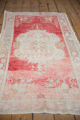 Distressed Oushak rug corner with cherry red, ivory field, and original side selvage.
