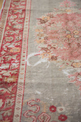 Distressed red border and abraded pale floral motifs on a vintage Oushak rug.