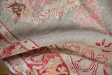 Textured distressed Oushak rug pile, with time-softened pale blush and cherry red patterns.