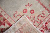 Hand-knotted Oushak rug close-up: distressed pile with foundation showing through, pale floral motifs.