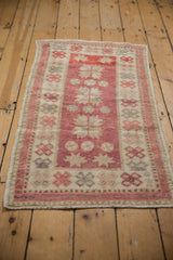 Distressed texture with raspberry red floral patterns on a vintage Oushak rug runner.