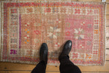 Distressed vintage Oushak rug detail showing faded pink and beige floral motifs.