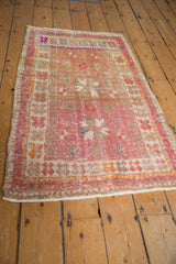 Distressed Oushak rug detail: faded pink field, worn texture, and orange-beige floral border.