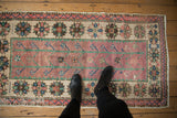 Distressed vintage Oushak runner, pale grape and emerald plant motifs with softly worn texture.