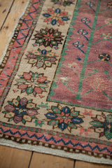 Distressed Oushak runner's worn border with floral clusters and emerald green tones.
