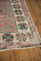 Distressed Oushak runner edge with soft mauve field, ivory border, and colorful simplistic floral motifs.
