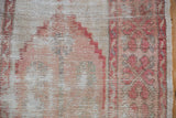 Distressed Oushak rug close-up: worn ivory, dusty rose pile, foundation visible.