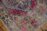Vintage distressed Oushak rug pile revealing rose, violet, and sand colored motifs.