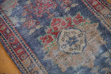 Scalloped trefoil medallion, faded red florals, and distressed navy blue pile of Oushak rug.