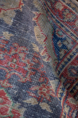 Distressed hand-knotted Oushak rug texture, showing faded navy, red, and beige.