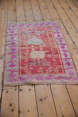 Close-up of vintage distressed Oushak rug shows abrashed red field, fuchsia floral border, and knot head wear.