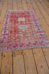 Distressed fringe and fuchsia floral border of a vintage Oushak rug with faded blue accents.