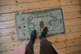 Distressed Oushak rug mat with an elongated blue medallion and seafoam green floral pattern.