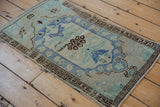Distressed Oushak rug texture with faded sky blue, beige, and ornate serrated leaf motifs.