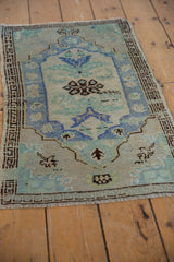 Distressed Oushak rug's blue and green serrated leaves, chocolate floral motifs, even wear.