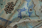 Evenly worn texture of a distressed Oushak rug, with blue, brown, and seafoam green.