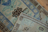 Distressed Oushak rug detail: worn pile, fringed edge, and blue, green, beige floral patterns.