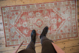 Distressed Oushak runner showcases faded madder red, ivory geometric patterns, and visible wear.