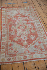 Distressed finned geometric patterns and stepped outlines in pale red and ivory on the Oushak rug.