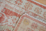 Close-up of the distressed Oushak rug's pale red and ivory pile, revealing its hand knotted reverse.