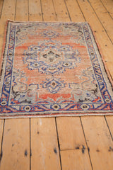 Distressed Oushak rug end with faded brick red and cobalt blue curvilinear patterns.