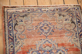 Distressed vintage Oushak rug corner, featuring faded rose and blue patterns, and visible knot heads.